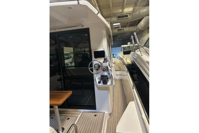 Slide: The Image of 2023 Nimbus C11 boat interior with steering console and wooden table in a showroom. - 27