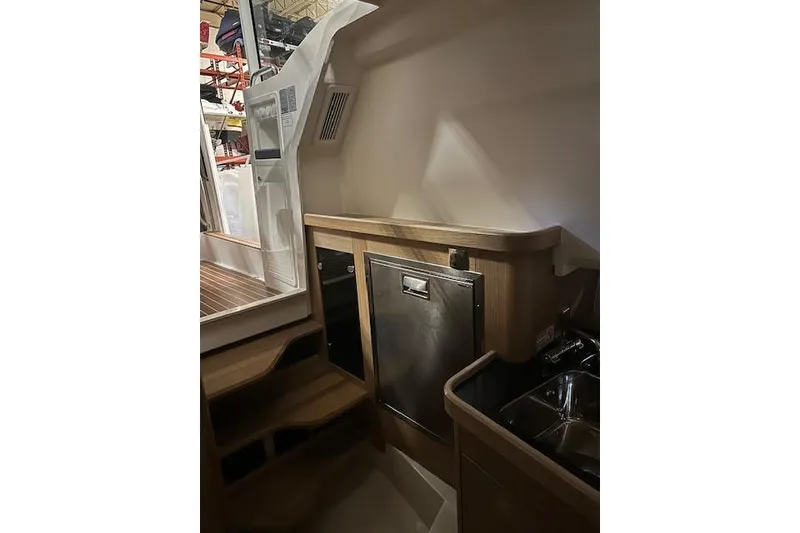 Slide: The Image of 2023 Nimbus C11 boat interior with wooden cabinetry and stainless steel appliances. - 3