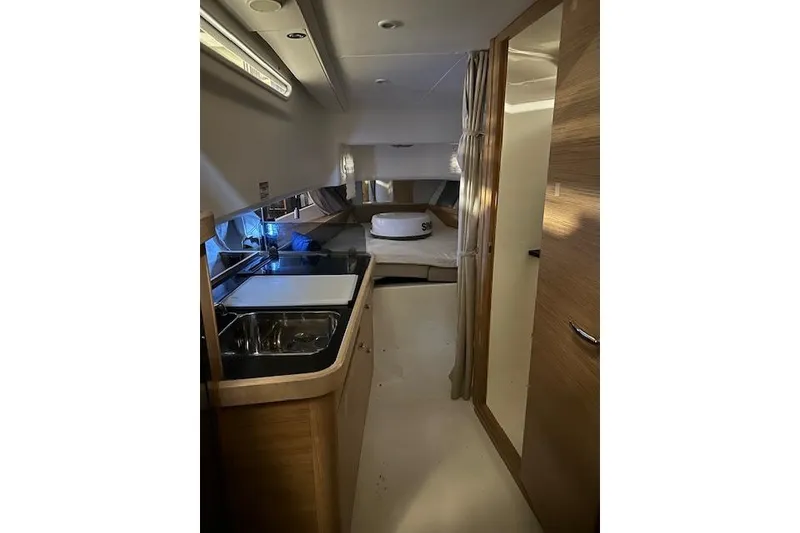 Slide: The Image of Interior of 2023 Nimbus C11 boat featuring a compact kitchen and cozy sleeping area. - 9