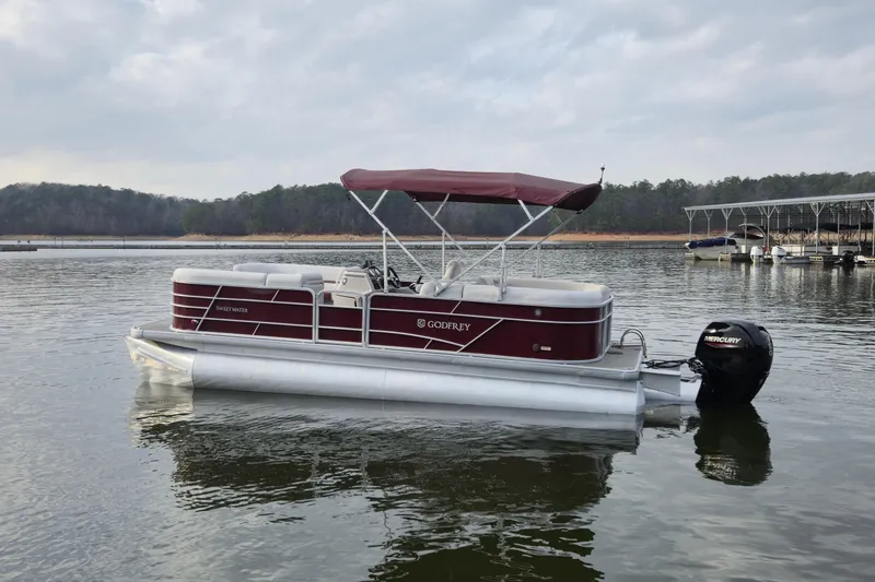 Slide: The Image of 2023 Godfrey Sweetwater 2286 C pontoon boat on a calm lake. - 5
