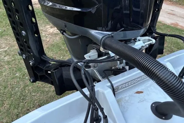 Slide: The Image of 2025 Freedom Boats 23' Warrior motor detail, showcasing engine and wiring on grass background. - 14