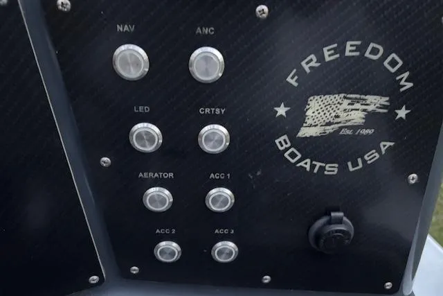 Slide: The Image of Control panel of 2025 Freedom Boats 23' Warrior, featuring various switches and logo. - 17
