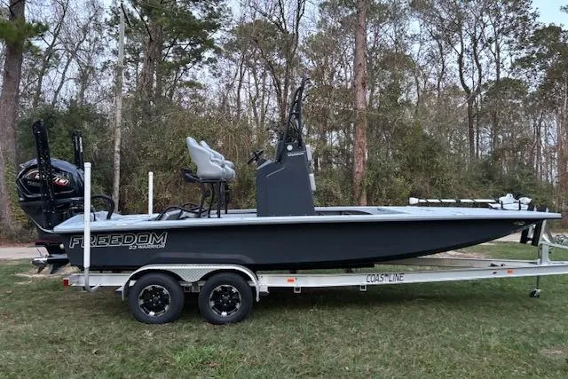 Slide: The Image of 2025 Freedom Boats 23' Warrior on trailer, parked in wooded area. - 3
