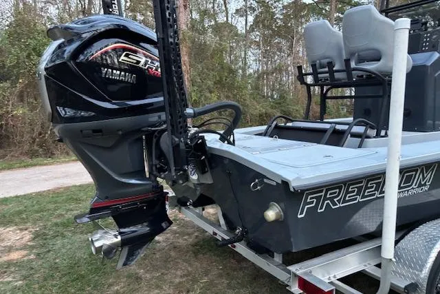 Slide: The Image of 2025 Freedom Boats 23' Warrior with Yamaha engine, parked on trailer in wooded area. - 4