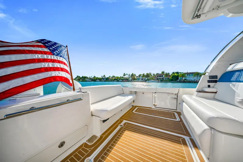 Slide: The Image of 2025 Hinckley Sport Boat 40 X deck with American flag, scenic waterfront view. - 4