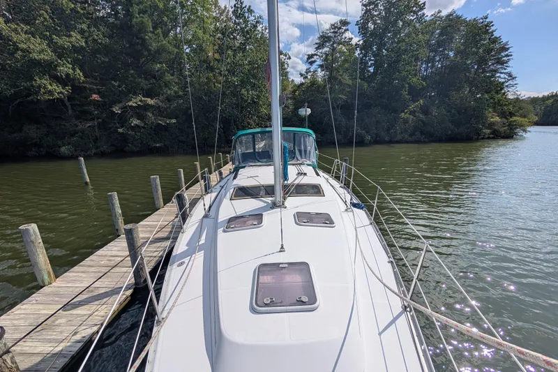 Slide: The Image of 2006 Beneteau Oceanis Clipper 373 docked by a serene, tree-lined waterway. - 6