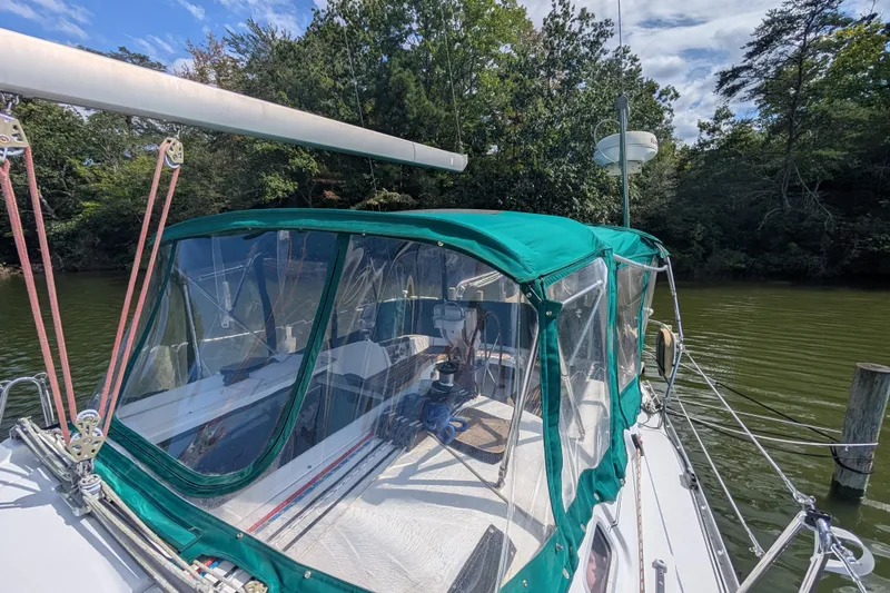 Slide: The Image of 2006 Beneteau Oceanis Clipper 373 sailboat with green canopy docked by lush trees. - 9