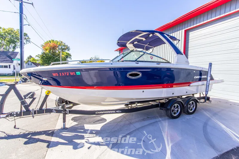 Slide: The Image of 2021 Chaparral 267 SSX boat on trailer, blue and white exterior, parked outside. - 10