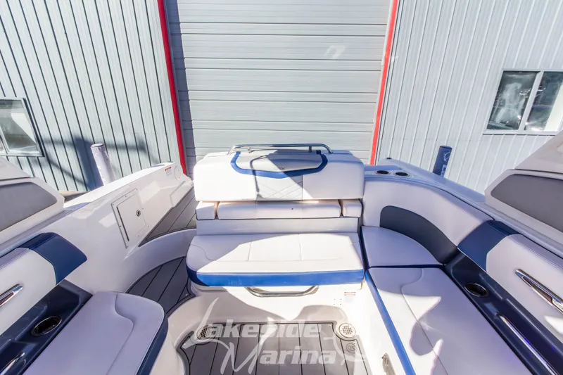 Slide: The Image of 2021 Chaparral 267 SSX boat interior with white and blue seating, docked at marina. - 18