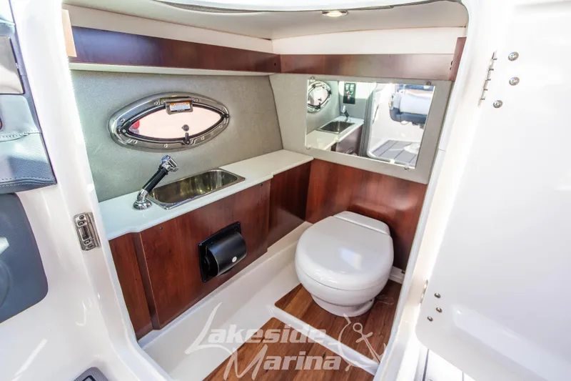 Slide: The Image of 2021 Chaparral 267 SSX boat bathroom with sink, toilet, and wood accents. - 29