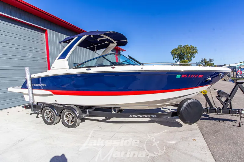 Slide: The Image of 2021 Chaparral 267 SSX boat on trailer, blue and white design, parked outdoors. - 3