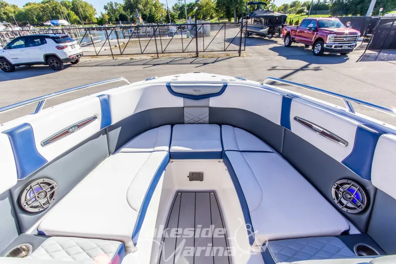 Slide: The Image of 2021 Chaparral 267 SSX boat interior with blue and white seating, parked at marina. - 33