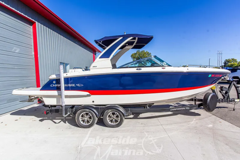 Slide: The Image of 2021 Chaparral 267 SSX boat on trailer, blue and white design, parked at marina. - 4