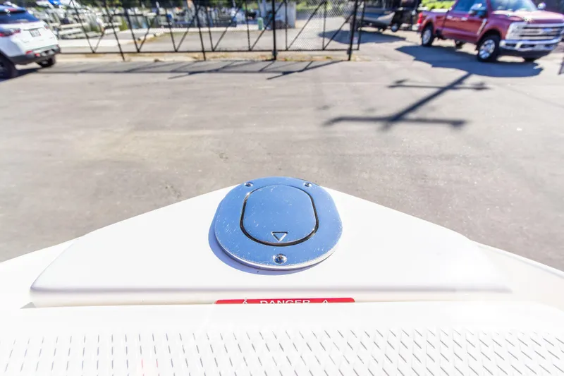 Slide: The Image of 2021 Chaparral 267 SSX boat bow with chrome hatch, parked near vehicles. - 41