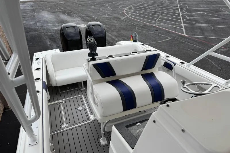 Slide: The Image of 2001 Intrepid 327 Center Console boat interior with white and blue seating, docked on asphalt. - 11