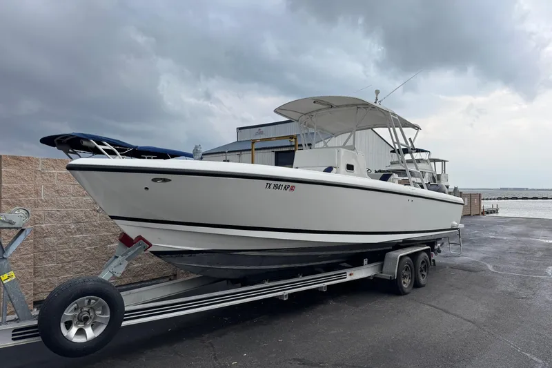 Slide: The Image of 2001 Intrepid 327 Center Console boat on trailer by waterfront under cloudy sky. - 3
