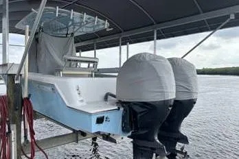 Slide: The Image of 2023 Contender 28 Sport boat with dual engines on a lift under a canopy. - 2