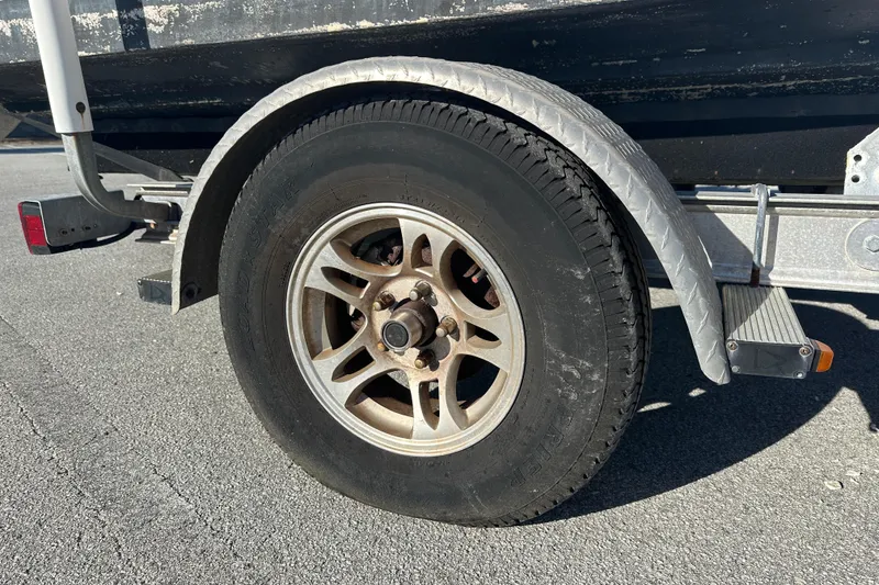 Slide: The Image of Trailer wheel of a 2004 Grady-White Sportsman 180 boat on asphalt. - 12