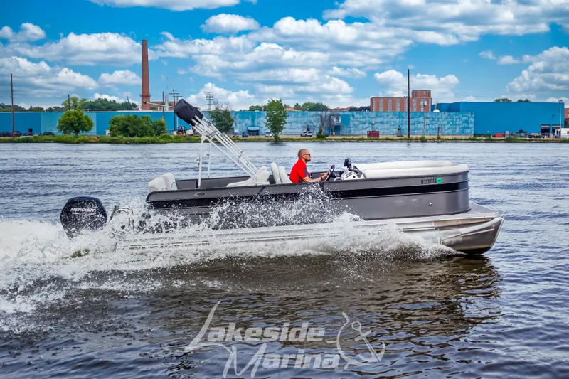 Slide: The Image of 2021 Crest Classic LX 220 SLRC pontoon boat cruising on a lake with a scenic backdrop. - 1