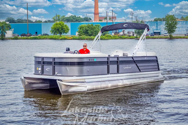 Slide: The Image of 2021 Crest Classic LX 220 SLRC pontoon boat on a lake with a person steering. - 12