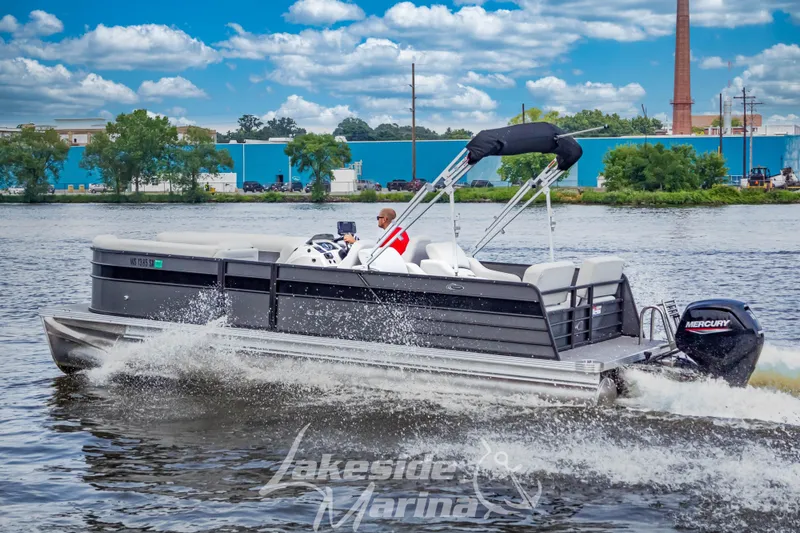 Slide: The Image of 2021 Crest Classic LX 220 SLRC pontoon boat cruising on a lake with a Mercury engine. - 2