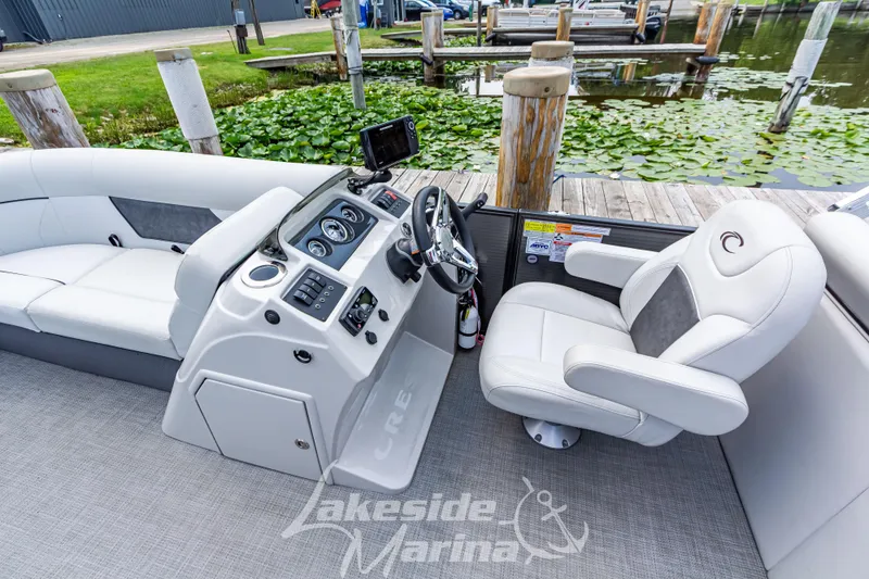 Slide: The Image of 2021 Crest Classic LX 220 SLRC boat interior with helm and seating at marina. - 21