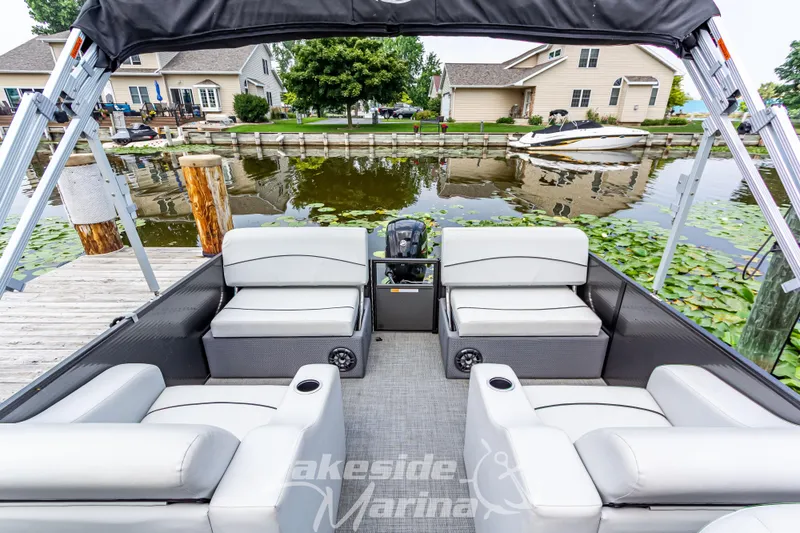 Slide: The Image of 2021 Crest Classic LX 220 SLRC pontoon boat with seating, docked by a lakeside marina. - 24