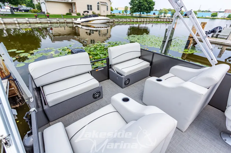 Slide: The Image of 2021 Crest Classic LX 220 SLRC pontoon boat with luxurious seating by a lakeside marina. - 25
