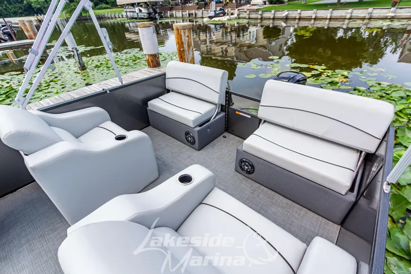 Slide: The Image of 2021 Crest Classic LX 220 SLRC pontoon boat interior with comfortable seating by a lakeside. - 26