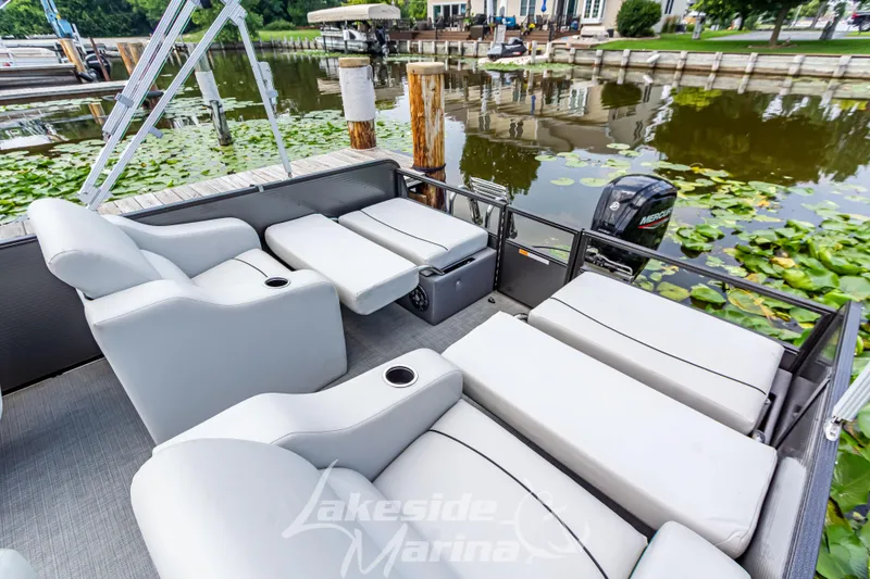 Slide: The Image of 2021 Crest Classic LX 220 SLRC pontoon boat with luxurious seating by a lakeside marina. - 29