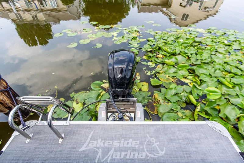 Slide: The Image of 2021 Crest Classic LX 220 SLRC pontoon boat with motor, surrounded by lily pads. - 33