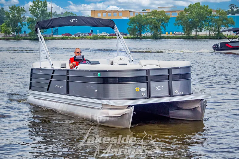 Slide: The Image of 2021 Crest Classic LX 220 SLRC pontoon boat cruising on a scenic lake. - 4
