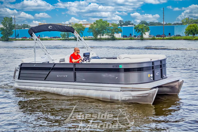 Slide: The Image of 2021 Crest Classic LX 220 SLRC pontoon boat cruising on a lake under a blue sky. - 5