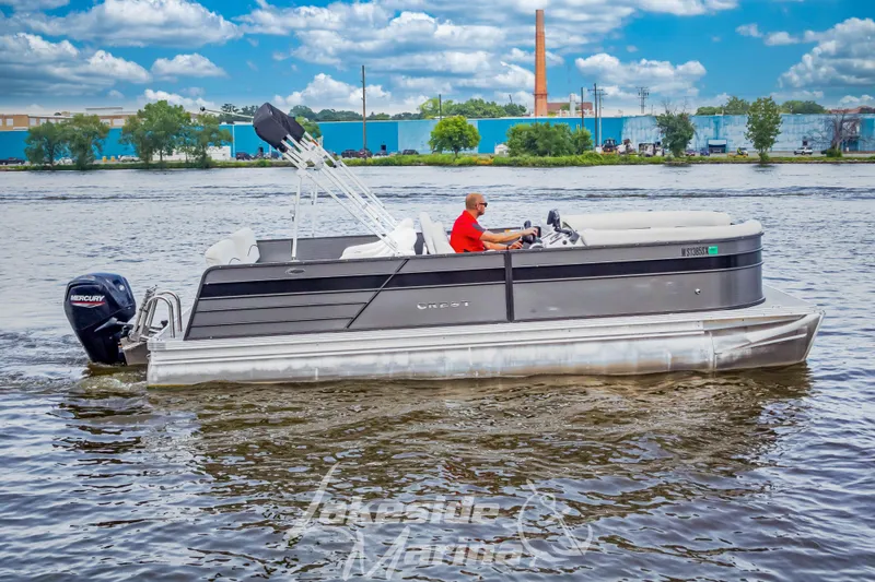 Slide: The Image of 2021 Crest Classic LX 220 SLRC pontoon boat cruising on a river under a blue sky. - 6