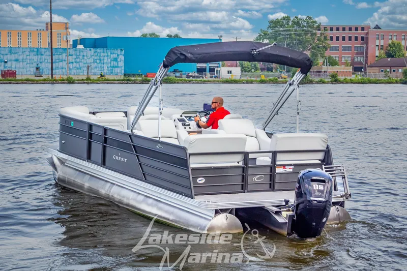 Slide: The Image of 2021 Crest Classic LX 220 SLRC pontoon boat cruising on a river near urban buildings. - 9