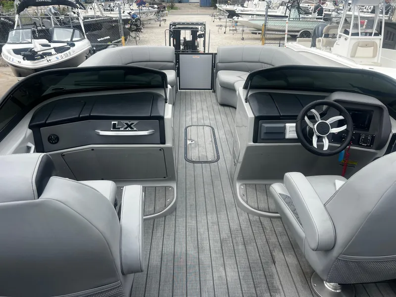 Slide: The Image of 2022 Manitou 27 boat interior with gray seating and steering wheel, docked at marina. - 7