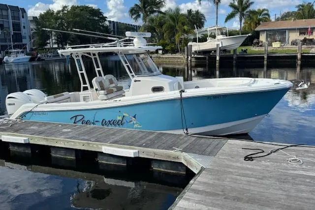 The Image of 2022 Edgewater 280CC boat docked, featuring a sleek blue and white design. - 0