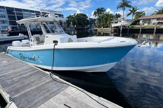 Slide: The Image of 2022 Edgewater 280CC boat docked on a sunny day, with palm trees in the background. - 1