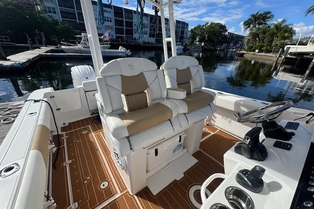 Slide: The Image of 2022 Edgewater 280CC boat interior with dual seats and modern controls, docked by waterfront. - 16