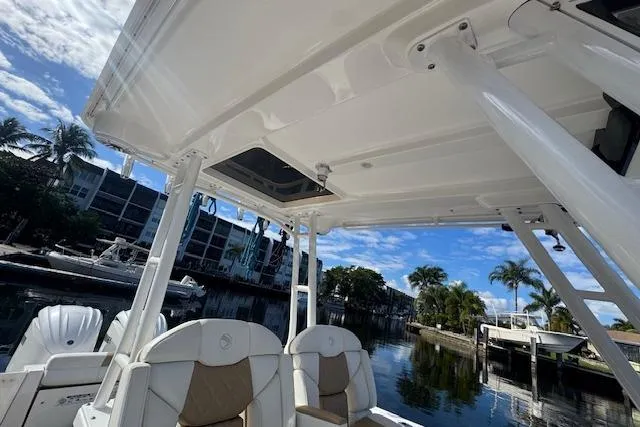 Slide: The Image of 2022 Edgewater 280CC boat interior with seating, docked near waterfront homes. - 17