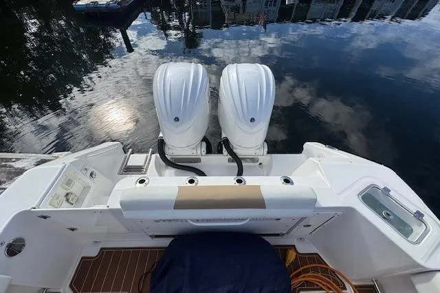 Slide: The Image of 2022 Edgewater 280CC boat with dual engines, docked on calm water. - 19