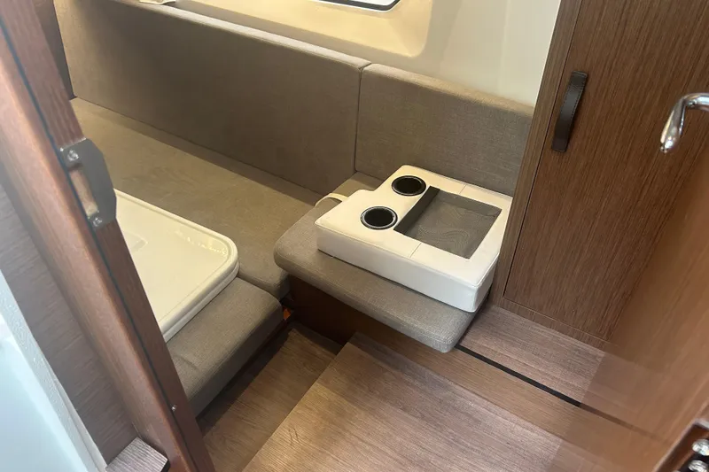 Slide: The Image of 2025 Beneteau Antares 11 Coupe interior with white seating and wooden flooring. - 23