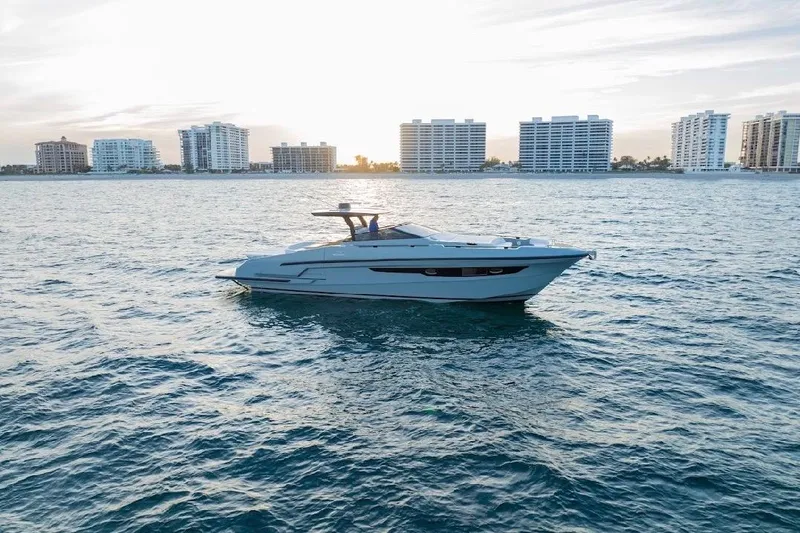 Slide: The Image of 2024 Rio Yachts Daytona 50 cruising on water with city skyline backdrop. - 12