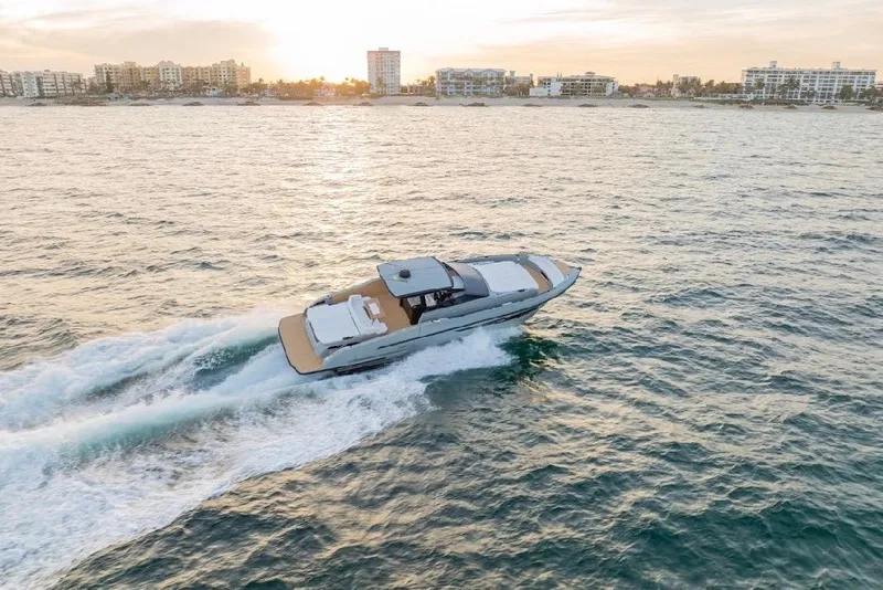 Slide: The Image of 2024 Rio Yachts Daytona 50 cruising at sunset near coastal city skyline. - 3