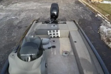 Slide: The Image of 2013 Tracker Super Guide V-16 SC boat interior with motor, on a paved surface. - 3