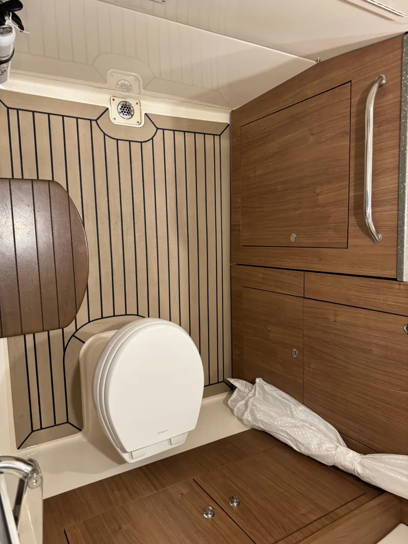 Slide: The Image of 2021 Boston Whaler 350 Outrage boat bathroom with wooden cabinetry and flooring. - 35