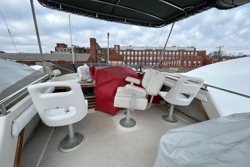 Slide: The Image of 1983 Silverton 34 Convertible boat deck with chairs, covered controls, and urban backdrop. - 14