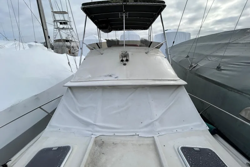 Slide: The Image of 1983 Silverton 34 Convertible boat covered in white tarp, docked among other vessels. - 19