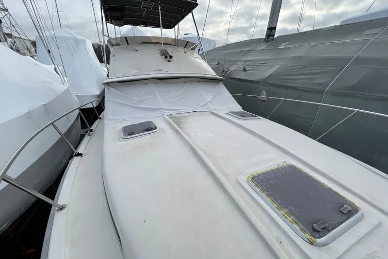 Slide: The Image of 1983 Silverton 34 Convertible boat docked, covered, and surrounded by other vessels. - 21