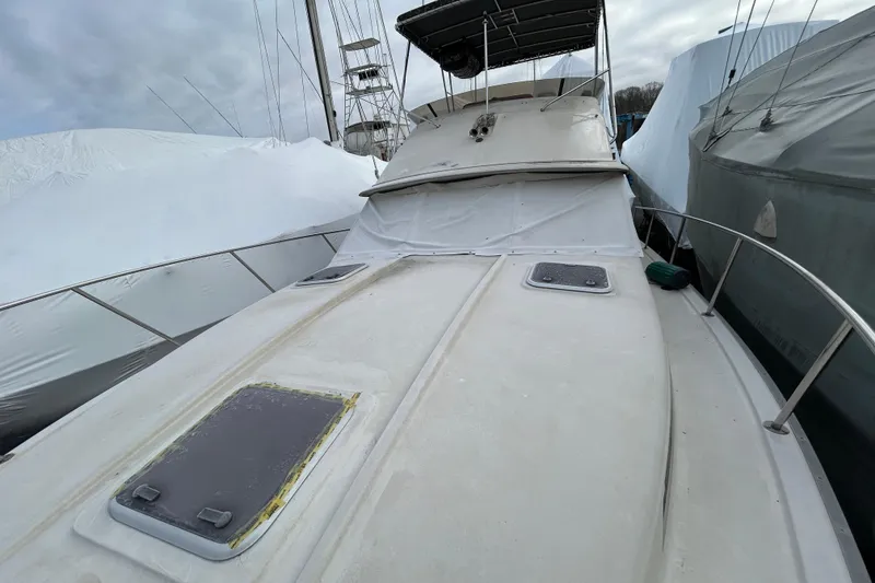 Slide: The Image of 1983 Silverton 34 Convertible boat covered and docked, surrounded by other vessels. - 22